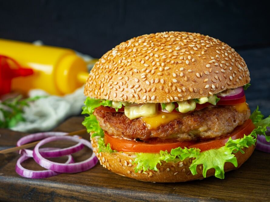 Homemade classic hamburger with beef cutlet, cheese, lettuce and tomato on dark background